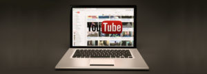 Laptop mit Startseite von YouTube vor dunklem Hintergrund