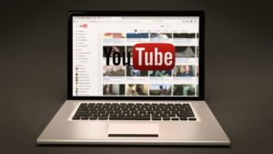 Laptop mit Startseite von YouTube vor dunklem Hintergrund